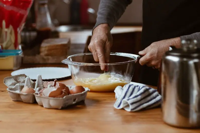 Person whisking eggs in a clear glass bowl
