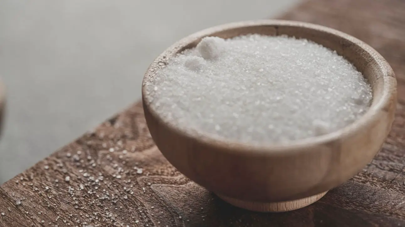 A wooden bowl filled with salt on top of a wooden table