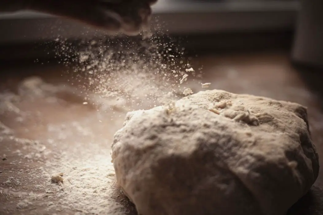 A person is sprinkling flour on bread dough