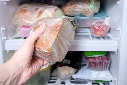 A person is putting bread in fridge
